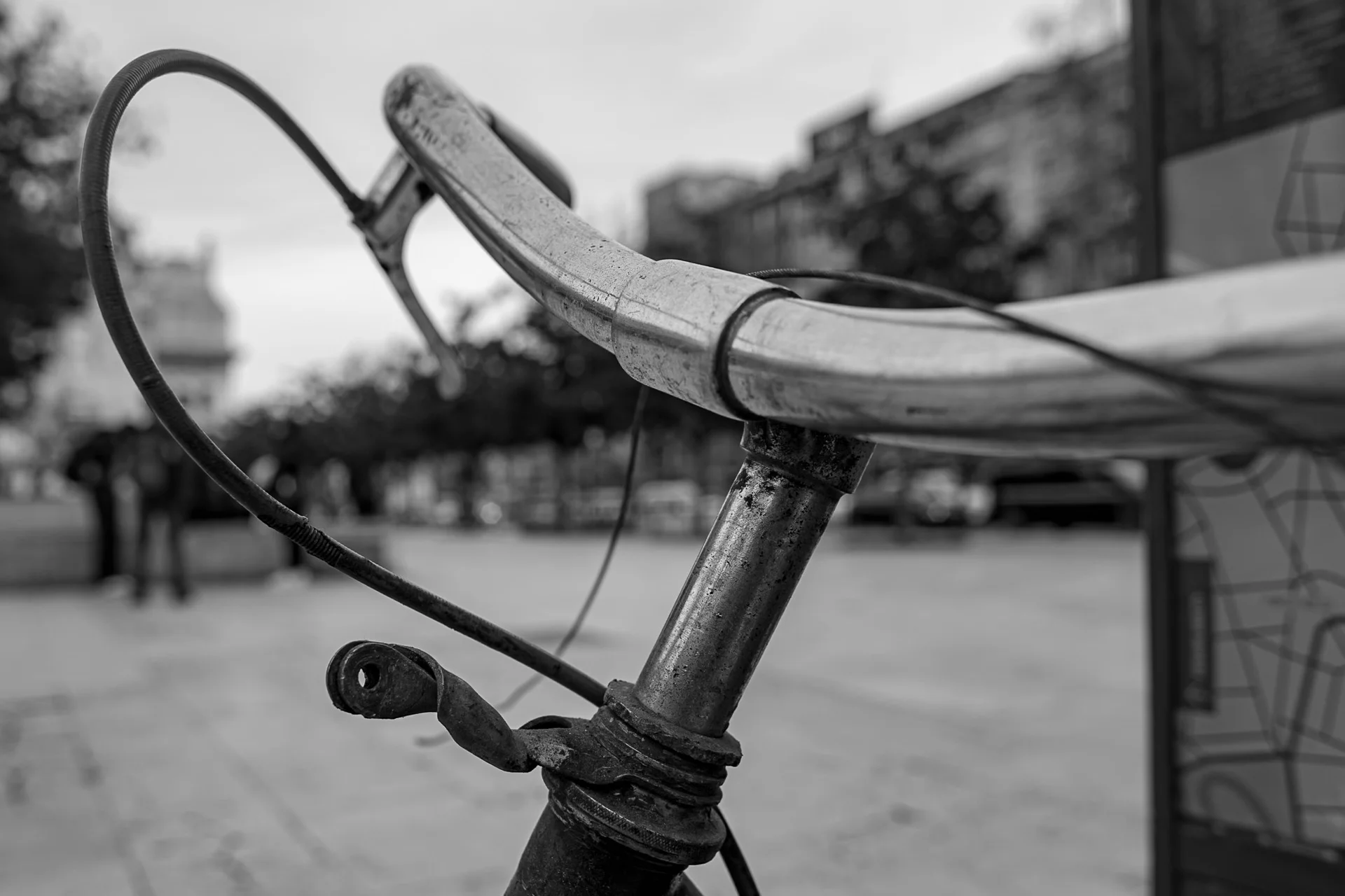 Detailed black-and-white photograph of a bicycle frame and handlebar leaning on a weathered wall, highlighting worn textures. | Leica Sl | N/A | f3.4 | 1/160s | ISO 100