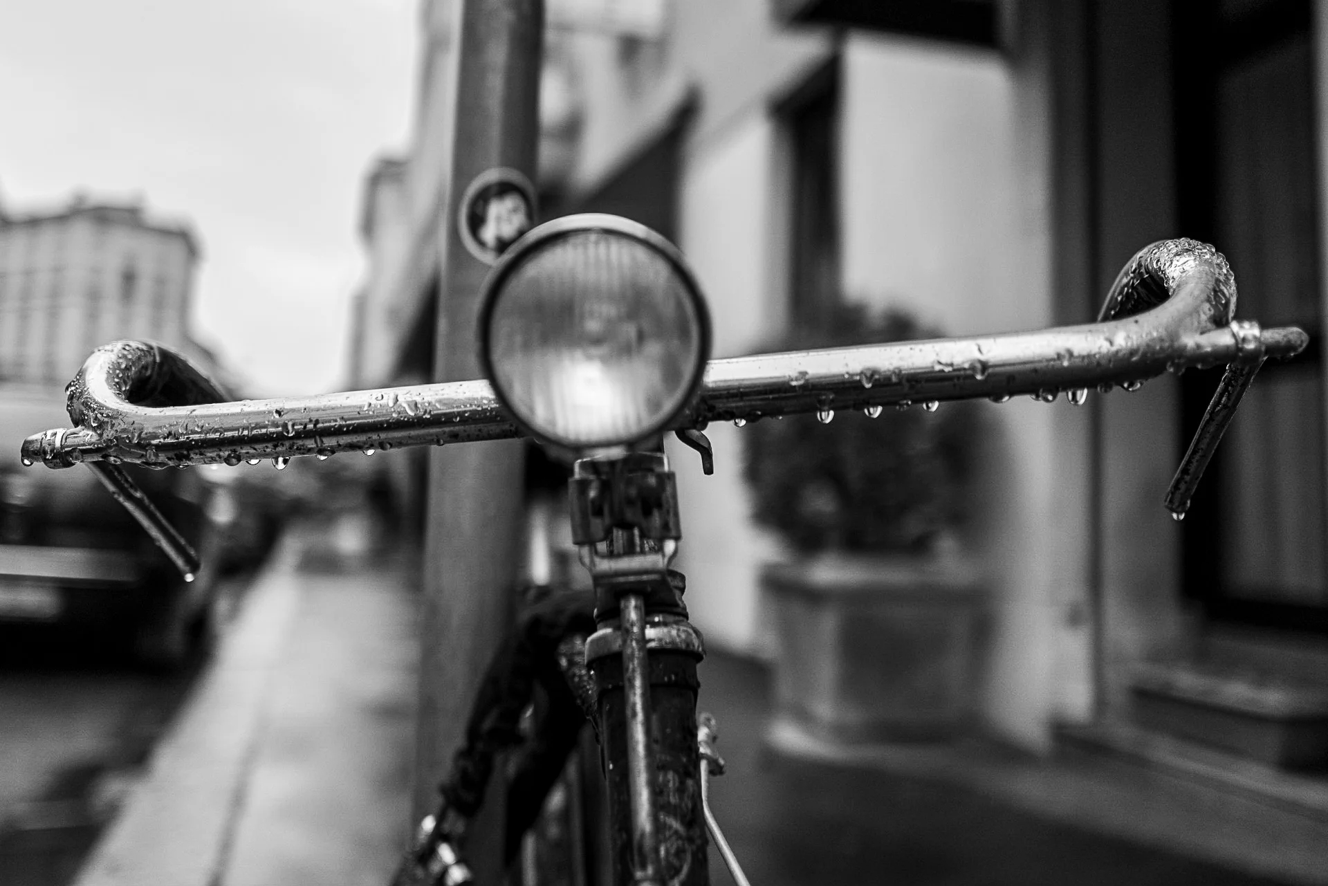 Black-and-white photograph of a vintage bicycle basket against an Italian street wall, showcasing mesh textures and reflective surfaces. | Leica Q2 | Summilux 28mm f1.7 | 28mm f/1.7 | 1/2000s | ISO 400