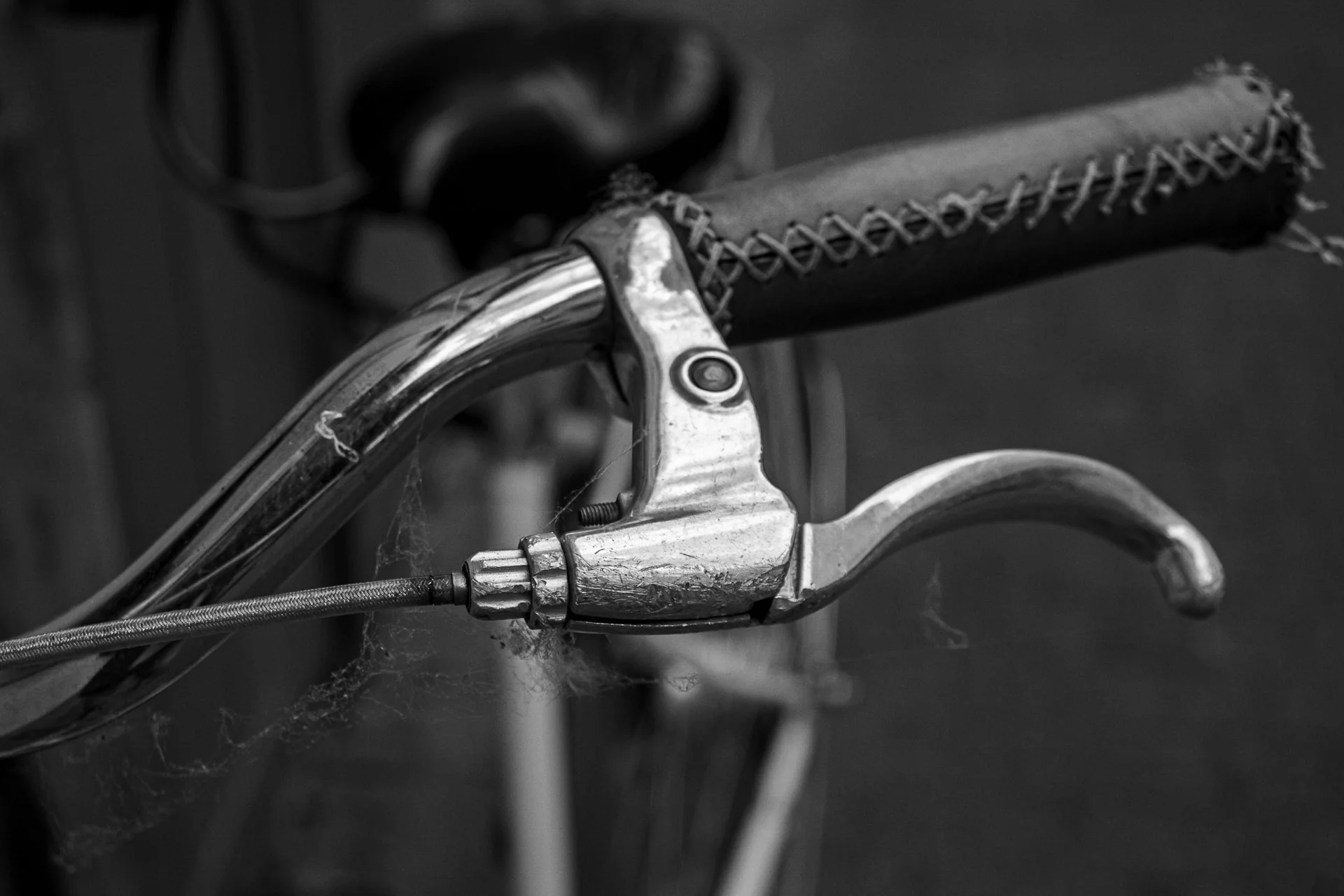 Black-and-white close-up of a bicycle brake lever and cable, highlighting fine mechanical textures. | Leica SL | N/A | f3.4 | 1/160s | ISO 100