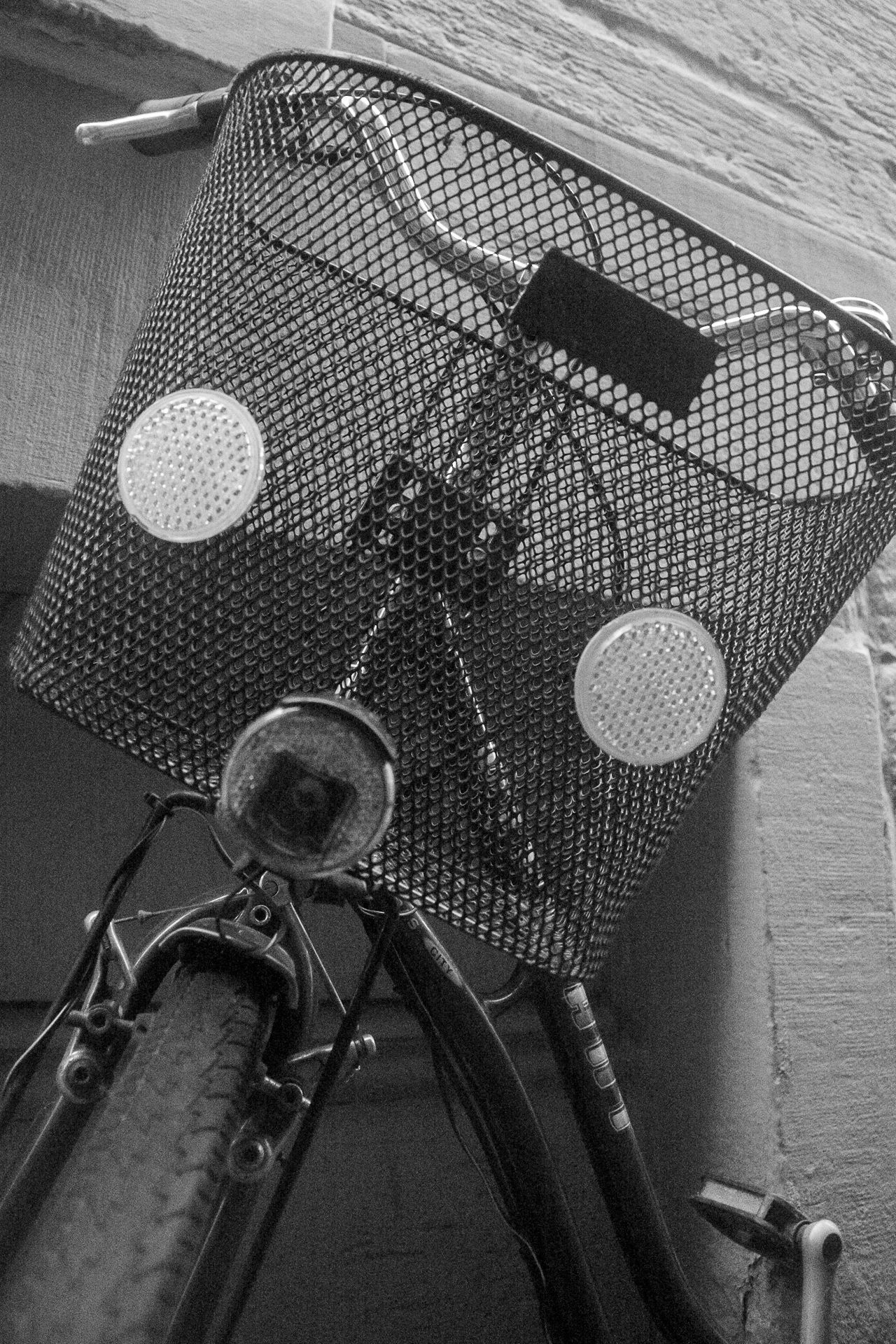 Black-and-white photograph of a bicycle basket from the front view, set in an Italian urban environment. | Leica SL | N/A | f2.8 | 1/320s | ISO 100