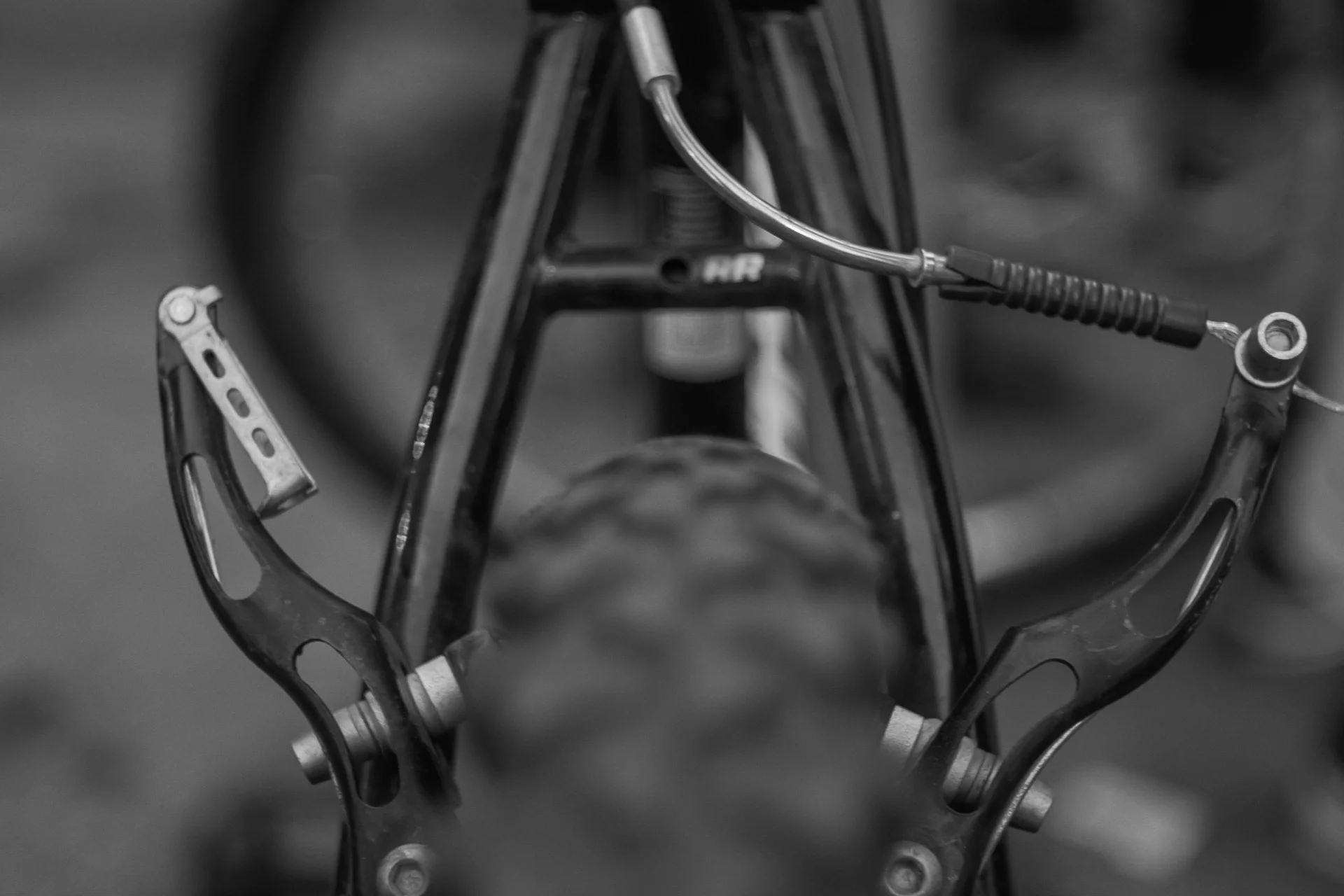 Black-and-white close-up of a bicycle brake mechanism and cable housing, emphasizing mechanical forms and textures. | Sony Alpha7 | 50mm | f3.5 | 1/500s | ISO 100
