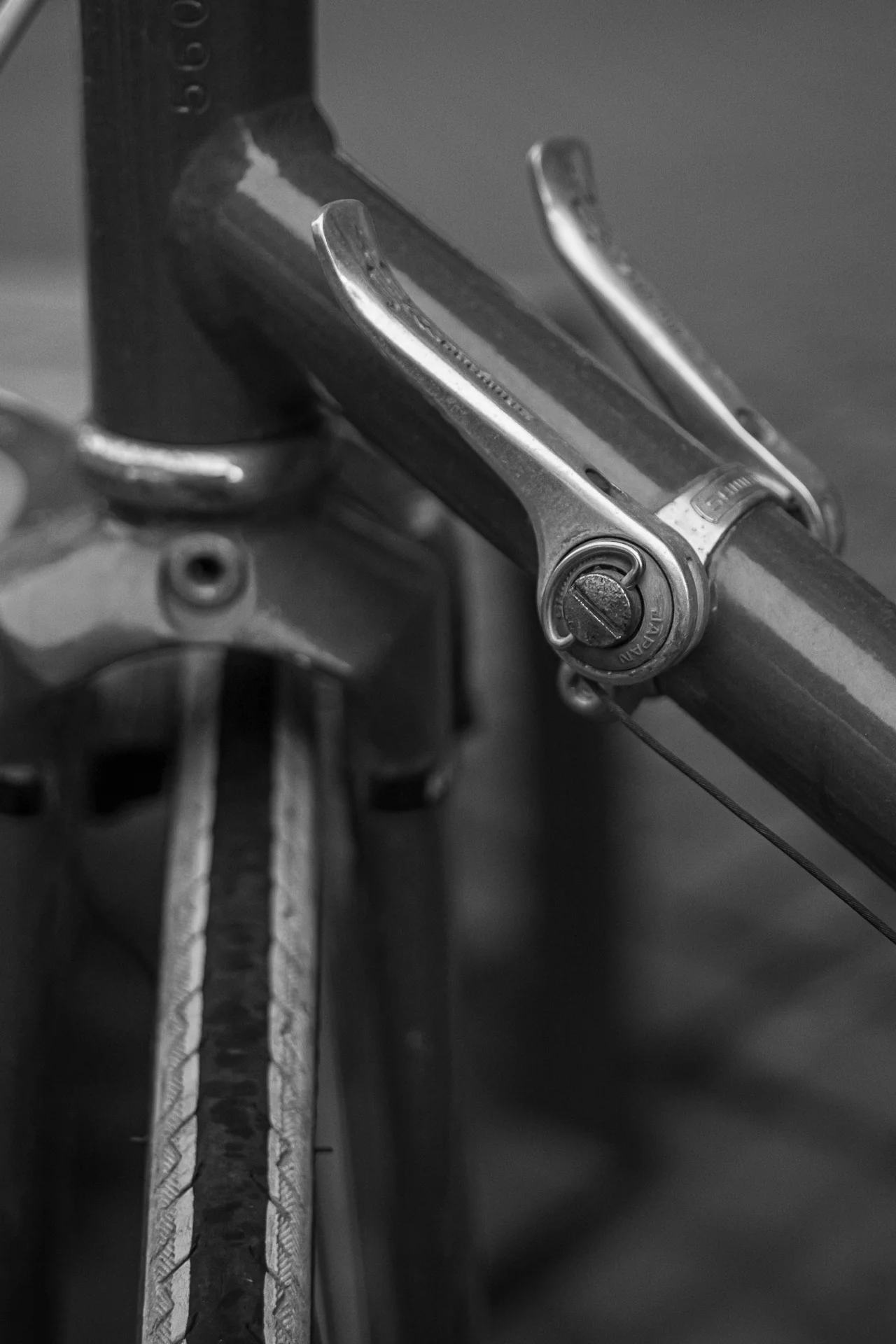 Black-and-white photograph of vintage bicycle shifter levers attached to the frame, showing polished metal and fine grooves. | Leica SL | N/A | f3.4 | 1/160s | ISO 100