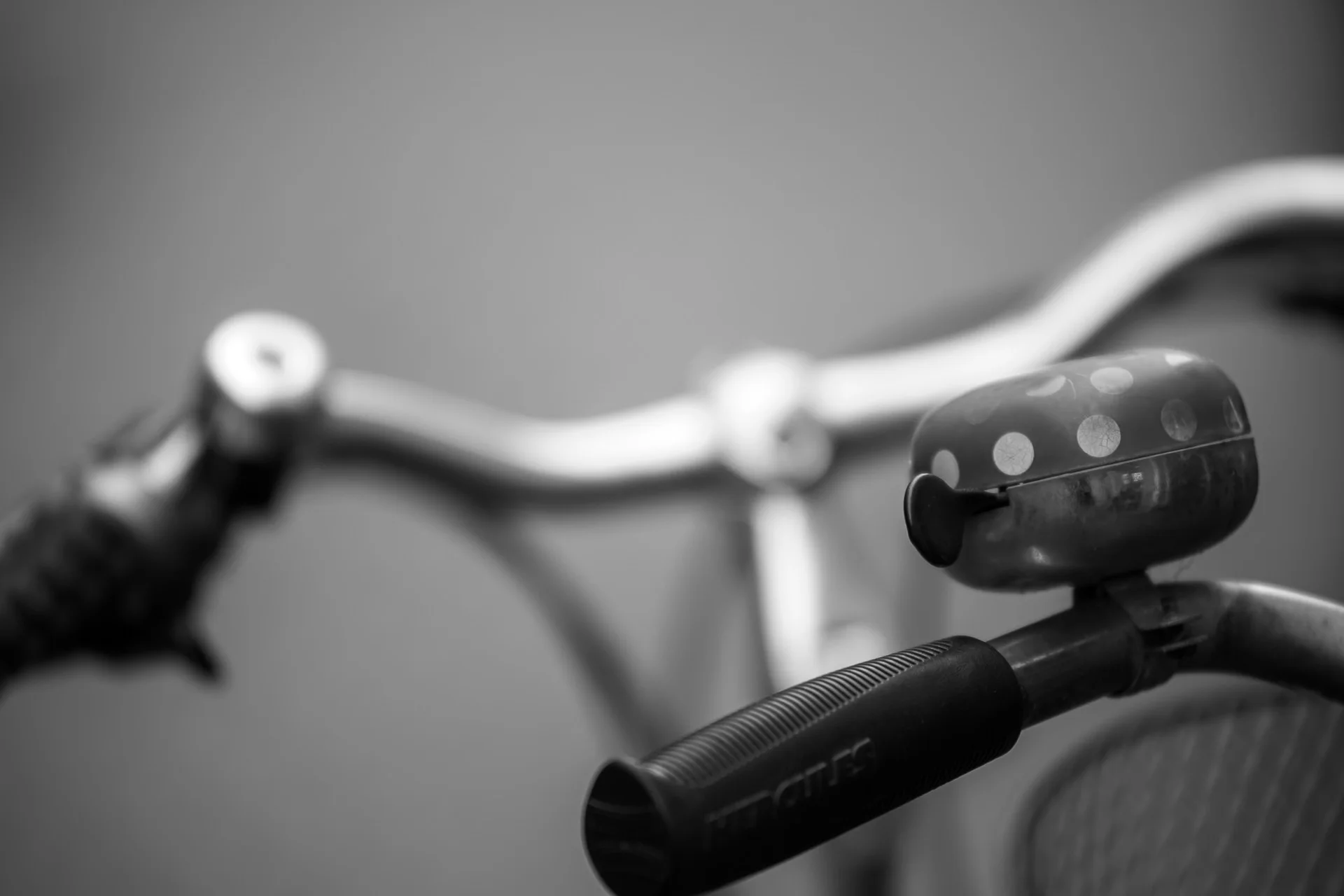 Black-and-white close-up of a bicycle bell with polka-dot pattern and textured rubber grip on handlebar. | Leica SL | N/A | f3.8 | 1/160s | ISO 100