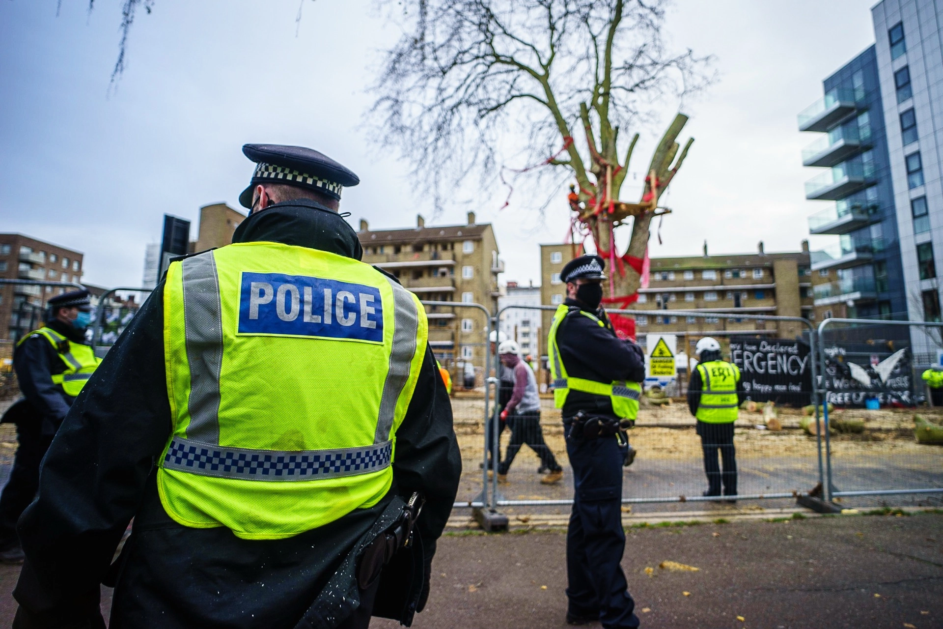 Police officers in high-visibility jackets at the Happy Man Tree protest site in Hackney, London. | Sony ILCE-7 (Alpha 7) | 18mm f/2.8 | 1/160s | ISO 100